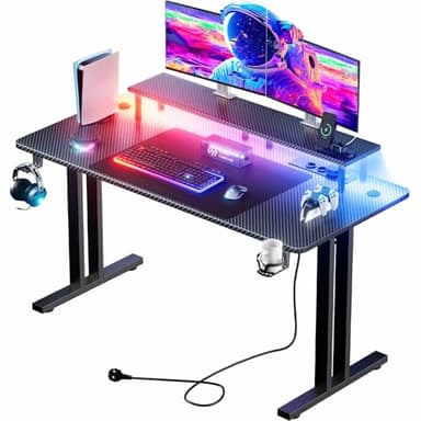HLFURNIEU Mesa Gaming LED 120 x 60 cm, Escritorio Gaming con Toma de Corriente y Soporte para Monitor, Mesa Gamer con Portavasos y Gancho para Auriculares, Superficie de Fibra de Carbono, Negro